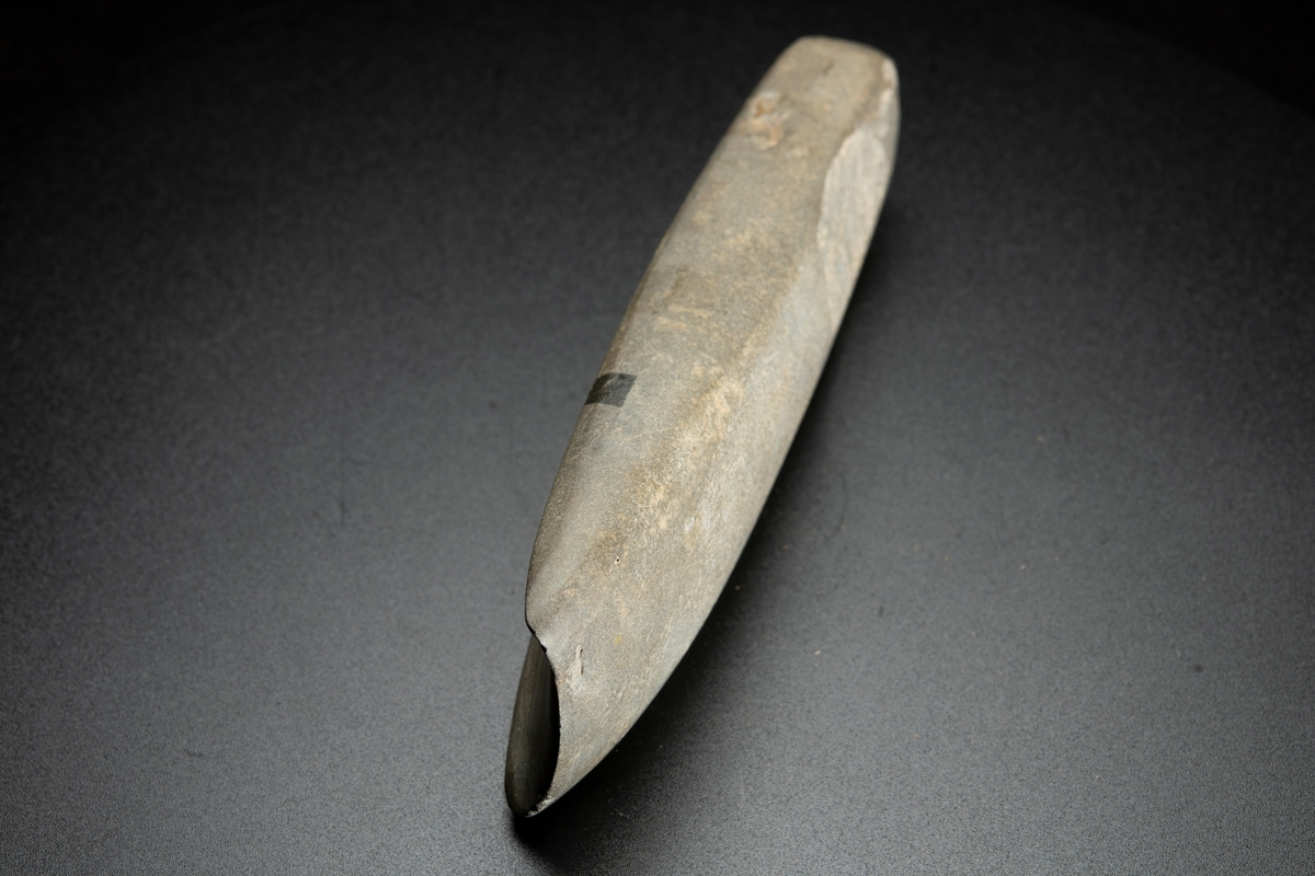 I det närmaste jämnbred. Fyrsidig. Kraftig hålslipning. Helt slipad. Av finkornig bergart.