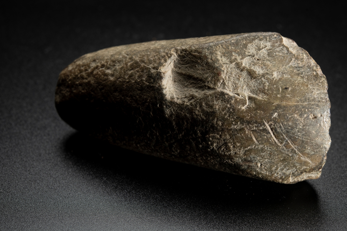 Baneparti av större yxa. Omslagen och omslipad för eggbildning. Starkt välvda bredsidor. Rund i nacken.