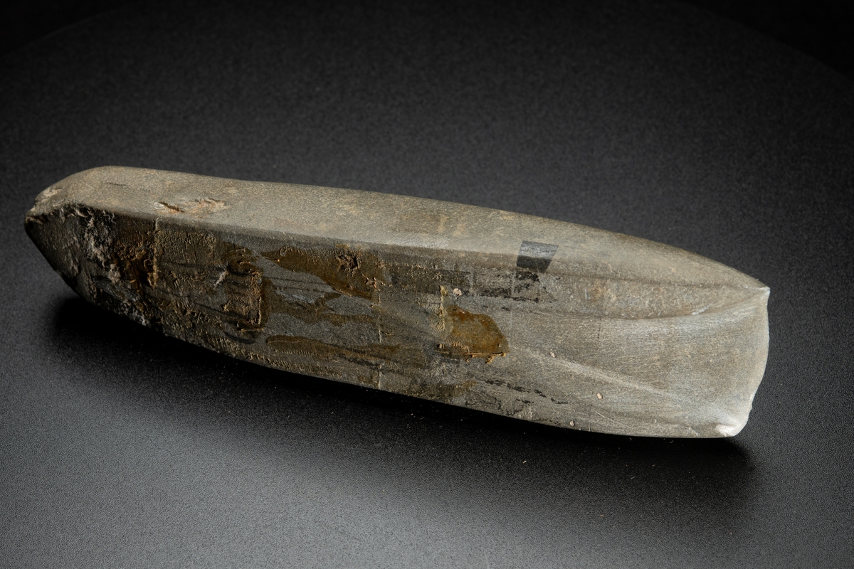 I det närmaste jämnbred. Fyrsidig. Kraftig hålslipning. Helt slipad. Av finkornig bergart.