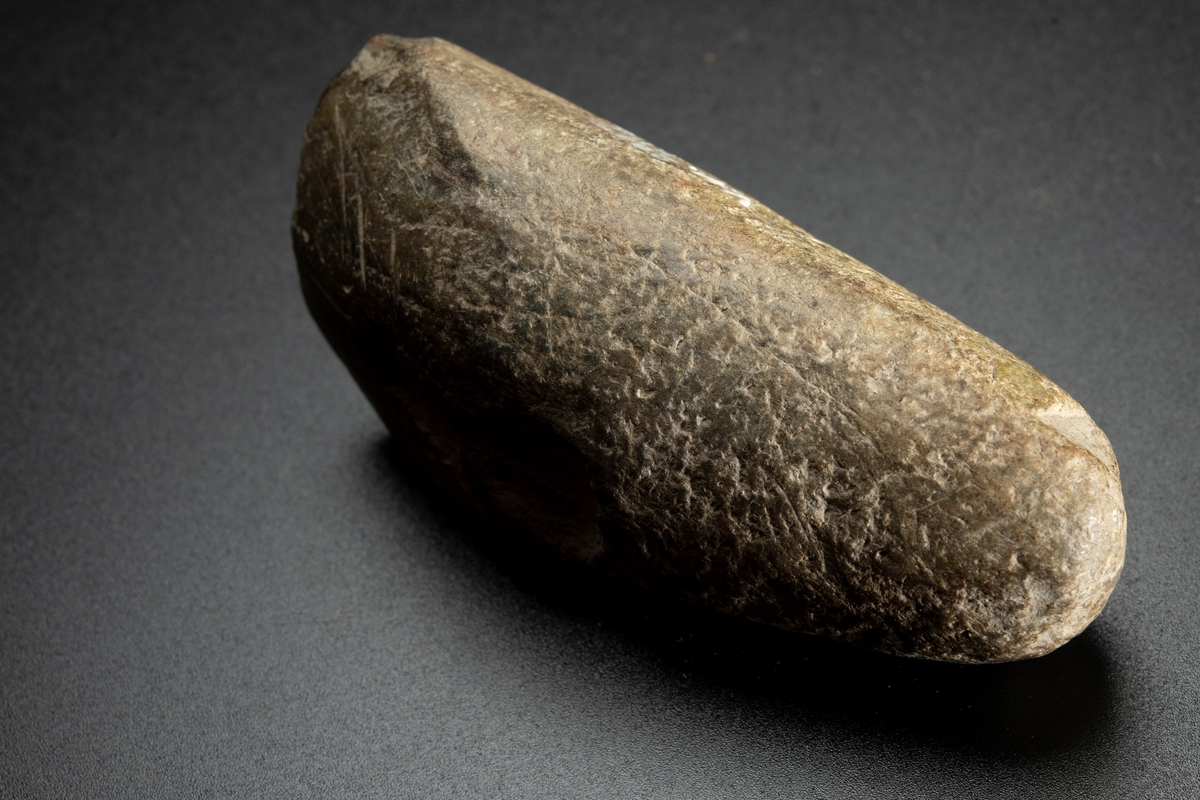 Baneparti av större yxa. Omslagen och omslipad för eggbildning. Starkt välvda bredsidor. Rund i nacken.