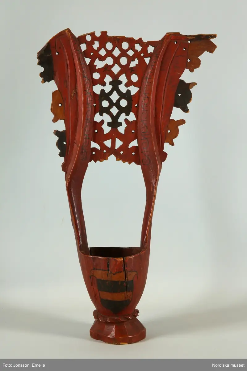 Katalogkort:
Kåsa av gran, rödmålad, omkr. 1590 (Cleve). Med Bielkes och Stures vapen (Hogenskild Bielke och Anna Sture, gifta 1569). Med ornament i svart färg."