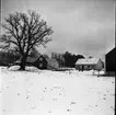 Ett nästan färdigbyggt hus syns på avstånd. Det ligger snö på marken.