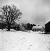 Ett nästan färdigbyggt hus syns på avstånd. Det ligger snö på marken.