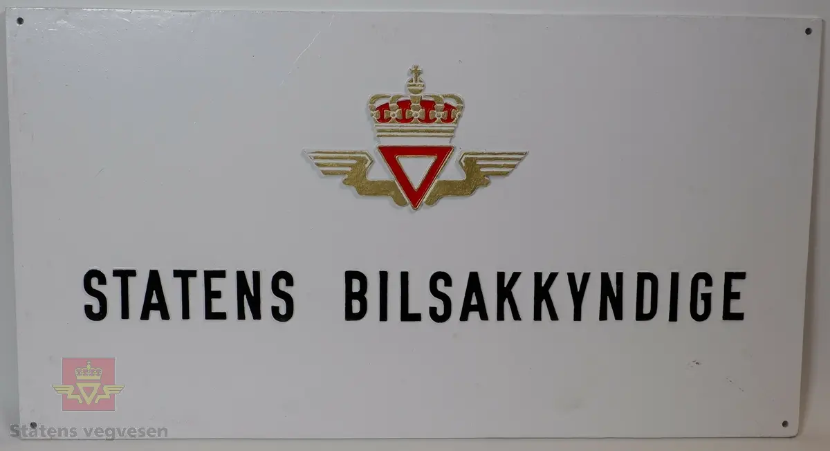 Rektangulært støpejerns skilt med fire hull for veggmontering. Etatslogo fra Statens Vegvesen samt påskriften "STATENS BILSAKKYNDIGE". Lakkert hvit med sort skrift. Rød og gullfarget logo. Bakside er ubehandlet støpejern. 