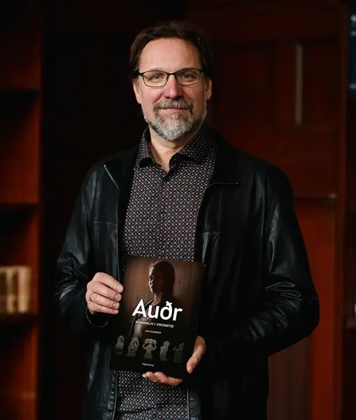 Bilde av historiker og forfatter Kim Hjardar. Han holder en bok i hånden og smiler mot kameraet.