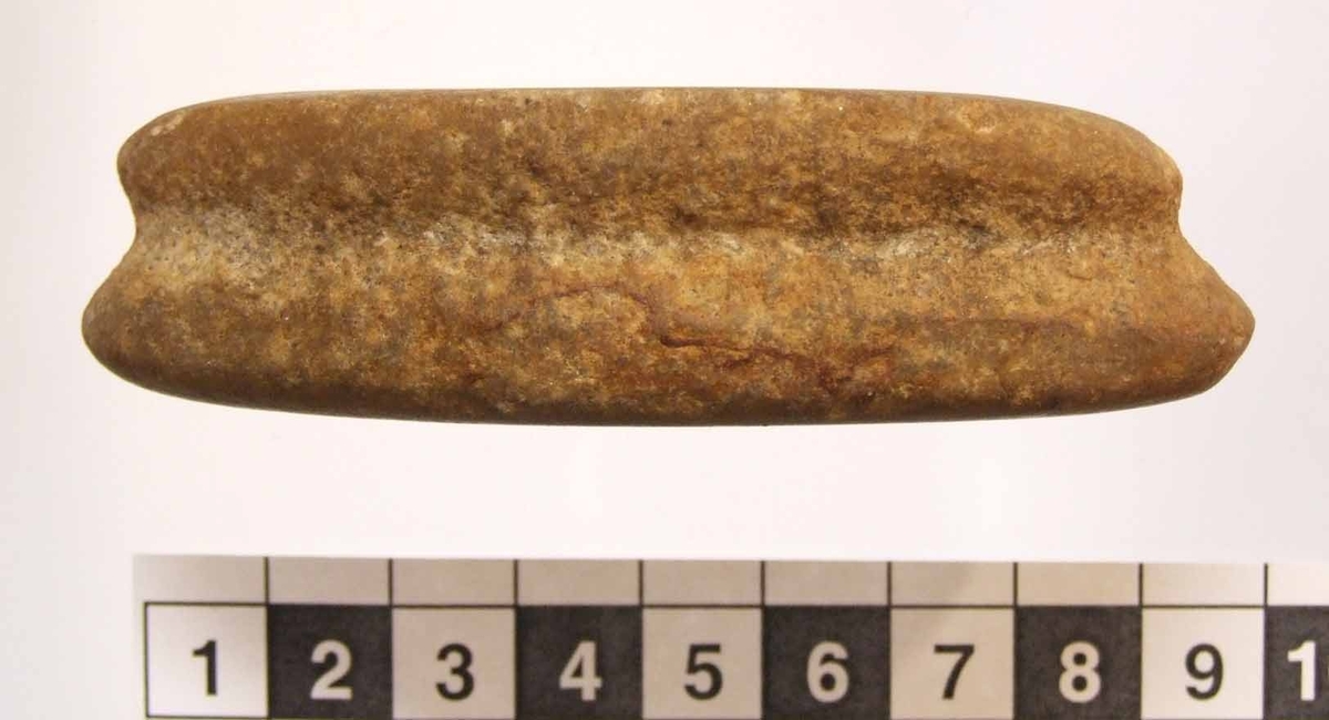 Eldslagningssten med spetsoval form. Ojämn v-formad ränna runt hela smalsidan, intill 9 mm bred och 2 mm djup. På ena flatsidan är ett 28 mm långt och 2-4 mm brett slagspår. Den andra flatsidan är svagt konkav.