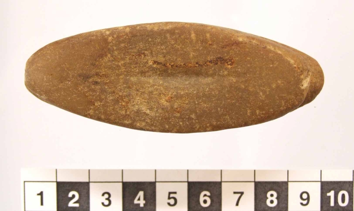 Eldslagningssten med spetsoval form. Ojämn v-formad ränna runt hela smalsidan, intill 9 mm bred och 2 mm djup. På ena flatsidan är ett 28 mm långt och 2-4 mm brett slagspår. Den andra flatsidan är svagt konkav.