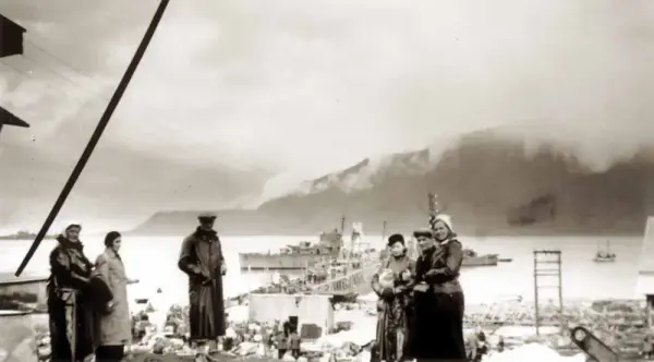 Mennesker evakueres fra kaia. Marinefartøy, fjord og fjell i bakgrunnen.