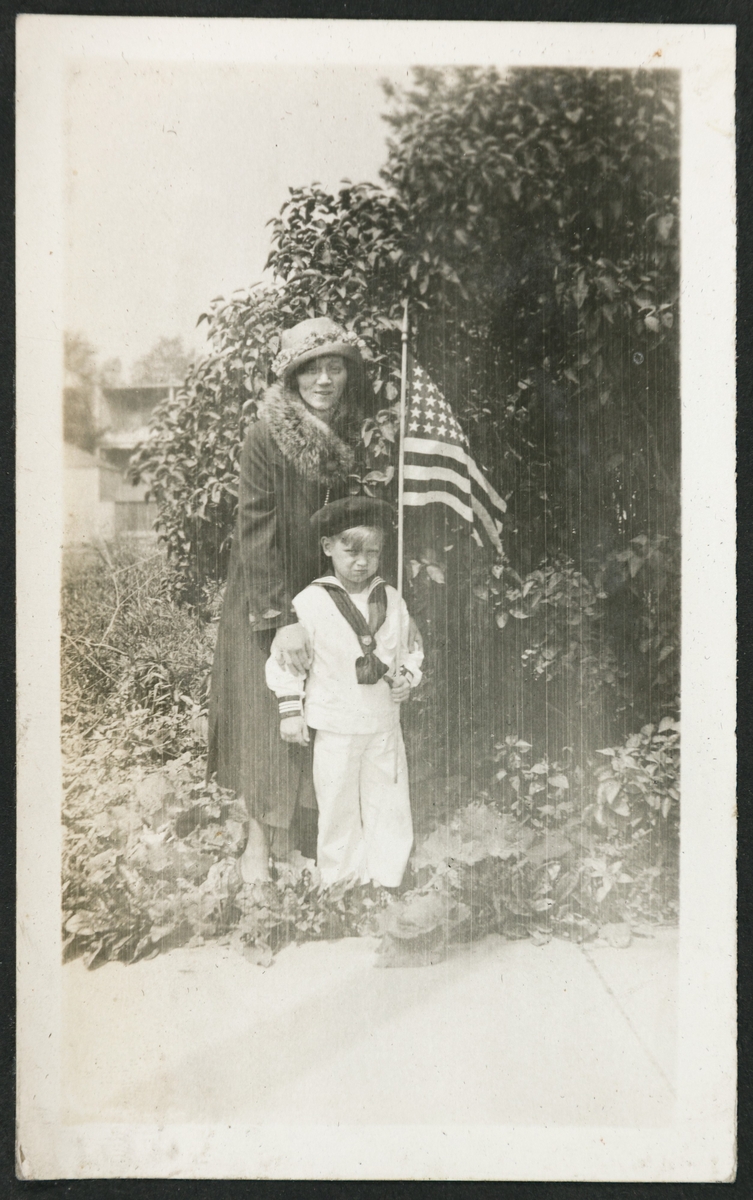Mrs. Ragnhild Bang og Billy i hagen i Ouster ave. Billy har matrosdress og et amerikansk flagg.
