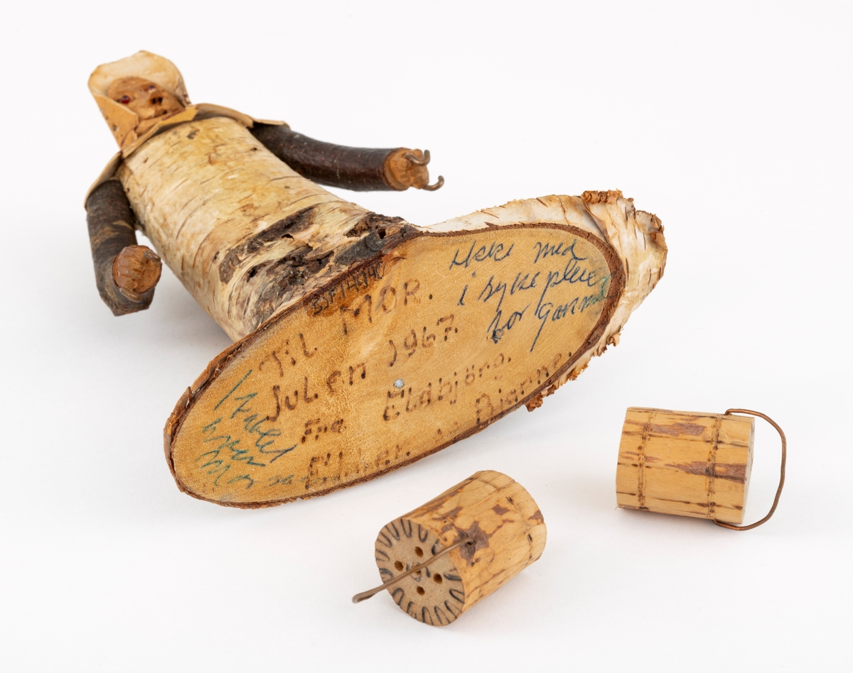 Trefigur spikket av tre, med påmontert never. Figuren er festet til en treplate.
Figuren er en etterligning etter moren til Eldbjørg Kordal, Ellen Pauline (f. Einarsrud) Kordal. Kona bærer ei vannbøtte i hver hand. Trefiguren var en gave fra Eldbjørg og hennes far jula 1967.