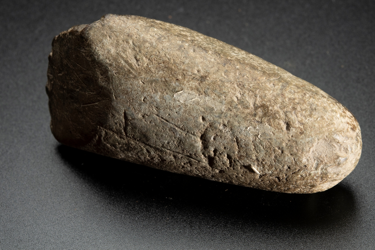 Baneparti av större yxa. Omslagen och omslipad för eggbildning. Starkt välvda bredsidor. Rund i nacken.