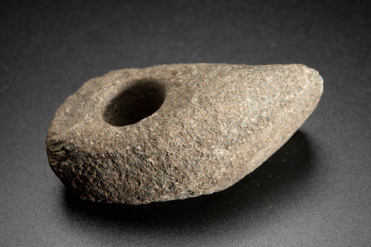 Liten, osymmetrisk. Eggen kraftigt snedvriden. Smalsidorna slipade mot eggen.