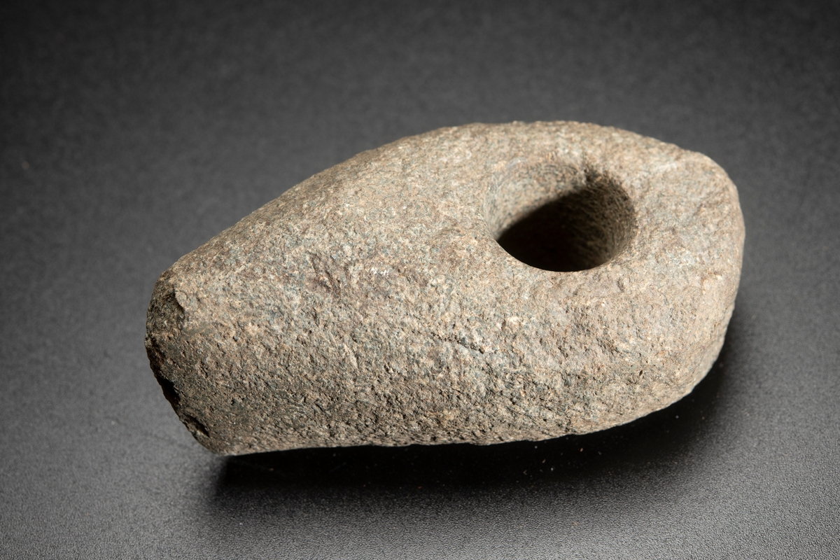 Liten, osymmetrisk. Eggen kraftigt snedvriden. Smalsidorna slipade mot eggen.