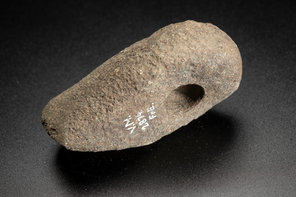 Liten, osymmetrisk. Eggen kraftigt snedvriden. Smalsidorna slipade mot eggen.