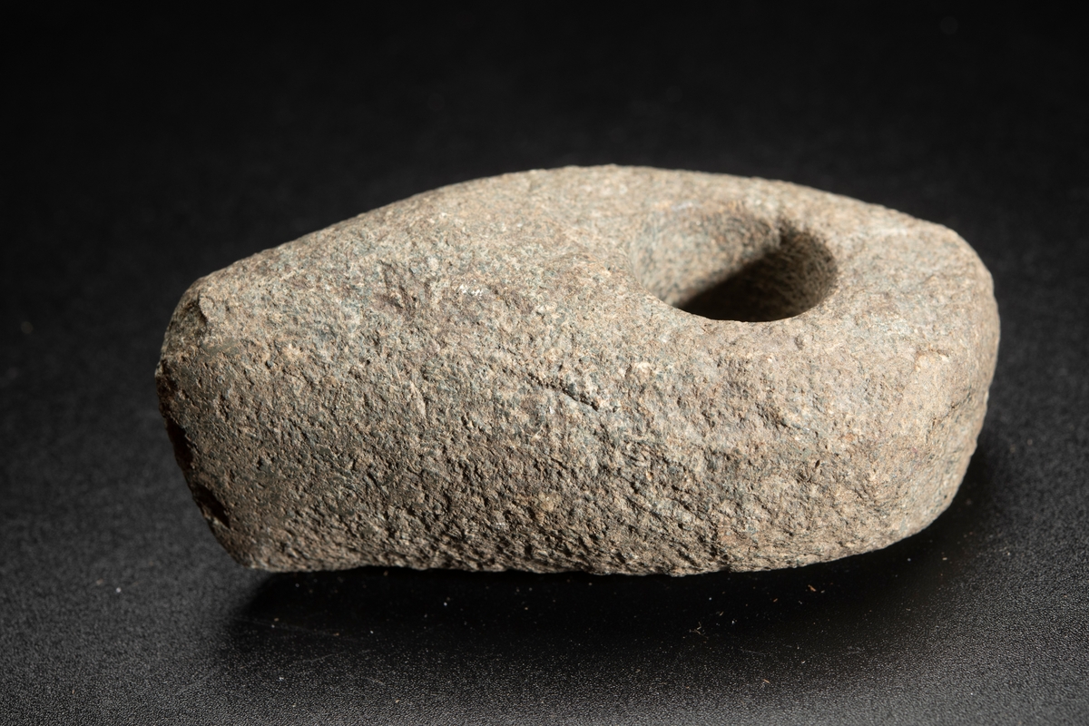 Liten, osymmetrisk. Eggen kraftigt snedvriden. Smalsidorna slipade mot eggen.