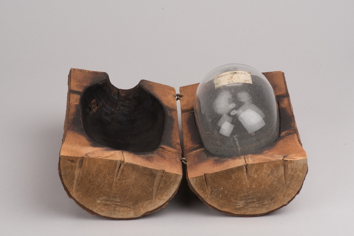 Påbörjad blåst glaskanna med träform.

Delbar form av trä som hålls ihop av märlor. På insidan utkarvad form för kanna. På utsidan två borrade hål, som inte är helt genomborrade, för redskapets grepp. På ovansidan öppning för glasmassan och inristat "B. 422". På undersidan tre inristade linjer.

Ämne till glaskanna, oval med avsmalnande hals och liten mynning. Drivet glas. Rundad botten. På sidan en klisteretikett.