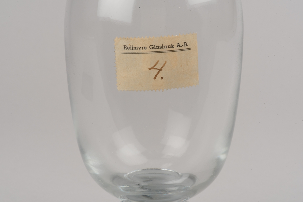 Ämne till kanna av drivet glas. 
Oval kanna som smalnar av mot fot och mynning. Rund, påklippt fot.