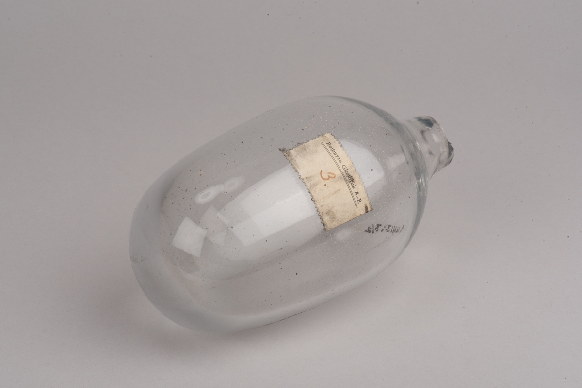 Påbörjad blåst glaskanna med träform.

Delbar form av trä som hålls ihop av märlor. På insidan utkarvad form för kanna. På utsidan två borrade hål, som inte är helt genomborrade, för redskapets grepp. På ovansidan öppning för glasmassan och inristat "B. 422". På undersidan tre inristade linjer.

Ämne till glaskanna, oval med avsmalnande hals och liten mynning. Drivet glas. Rundad botten. På sidan en klisteretikett.