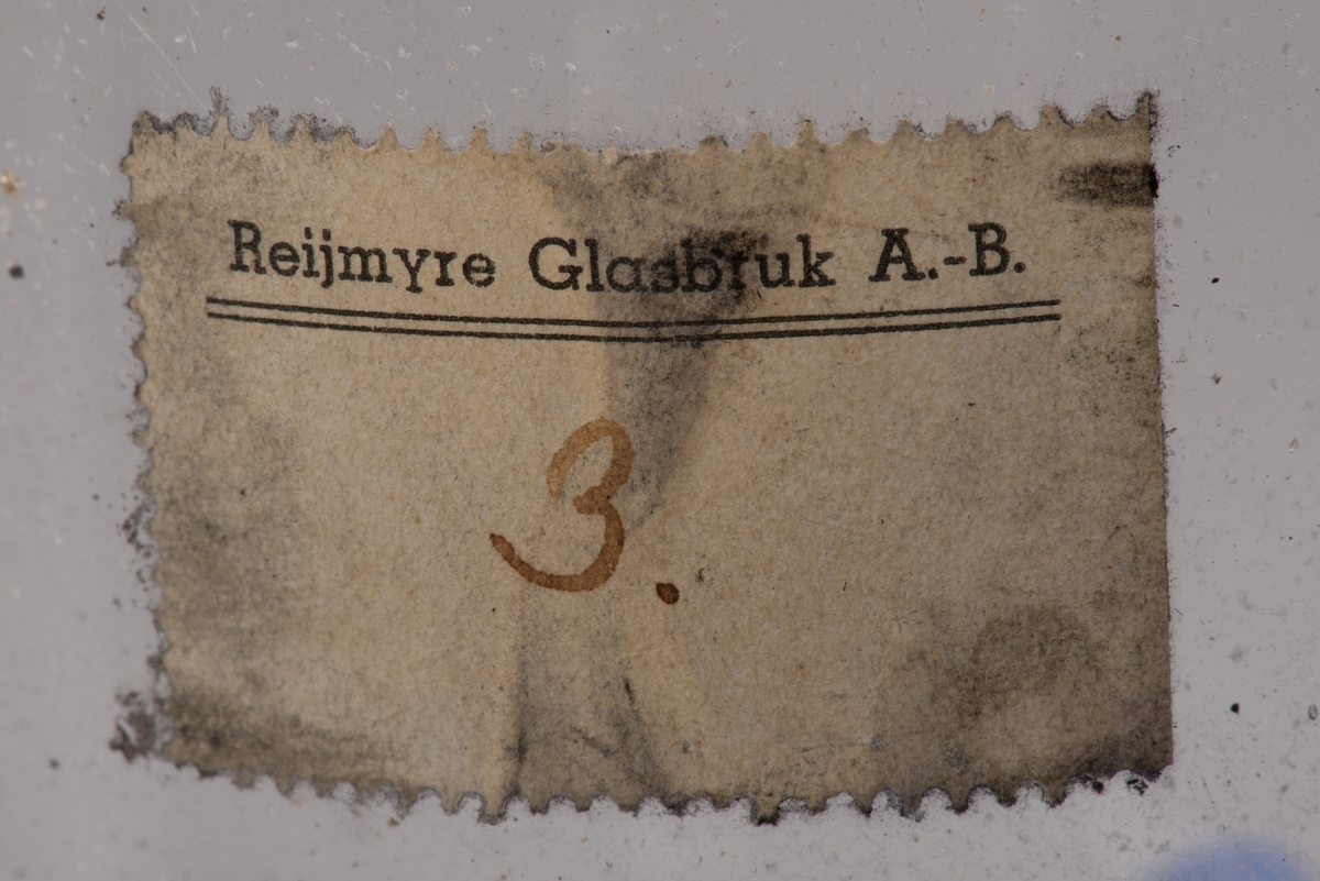 Påbörjad blåst glaskanna med träform.

Delbar form av trä som hålls ihop av märlor. På insidan utkarvad form för kanna. På utsidan två borrade hål, som inte är helt genomborrade, för redskapets grepp. På ovansidan öppning för glasmassan och inristat "B. 422". På undersidan tre inristade linjer.

Ämne till glaskanna, oval med avsmalnande hals och liten mynning. Drivet glas. Rundad botten. På sidan en klisteretikett.