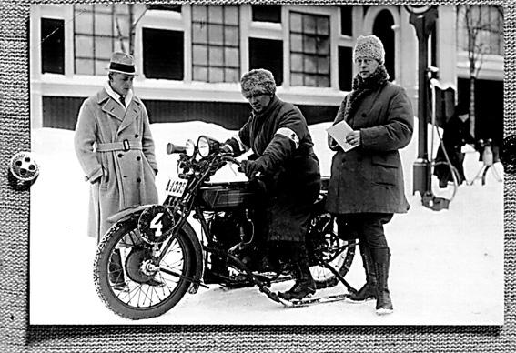 Tre män varav en på motorcykel med stödjande medar, klar för tävling med startnummer fyra.