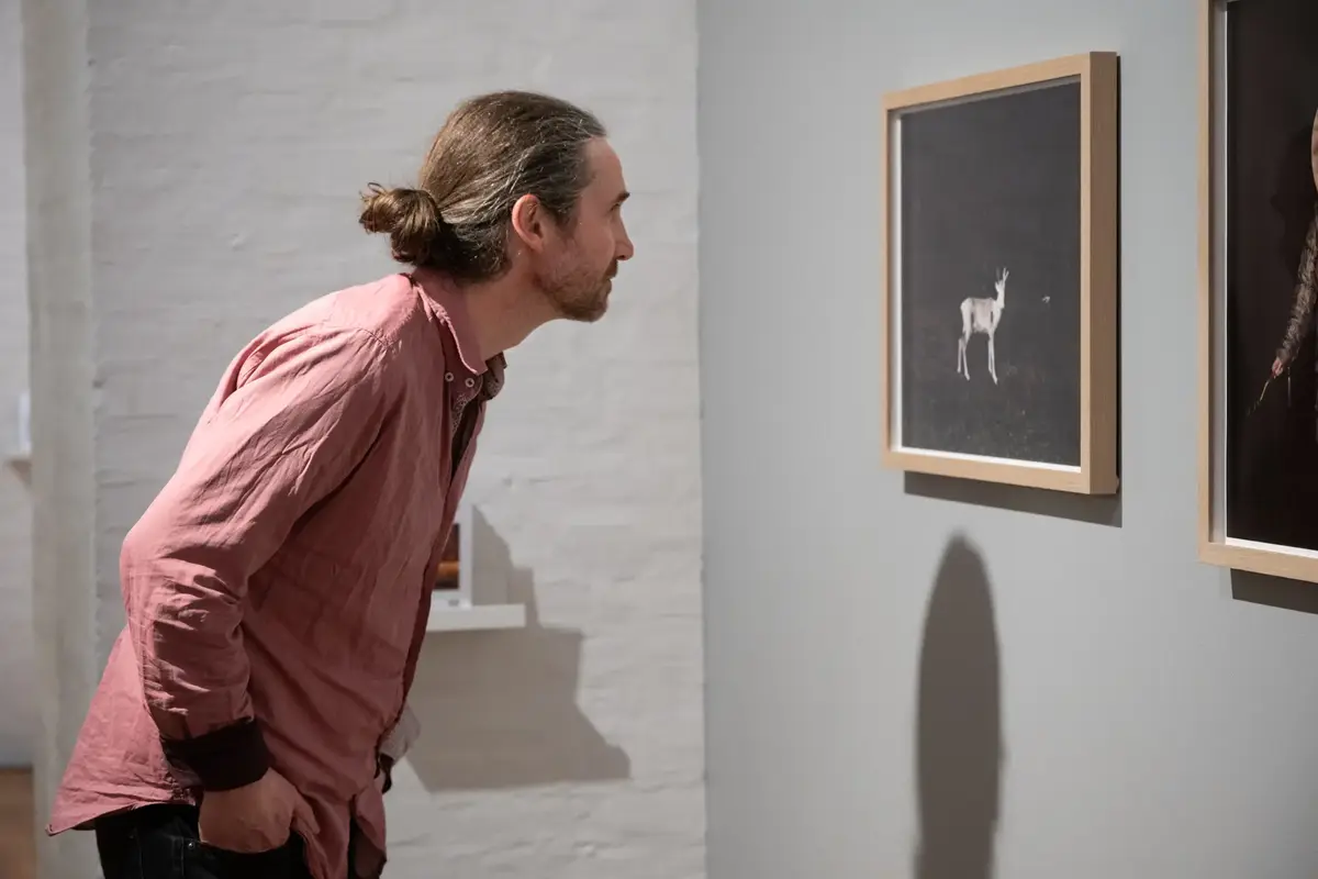 En mann i profil ser på et bilde på veggen. Fotografi