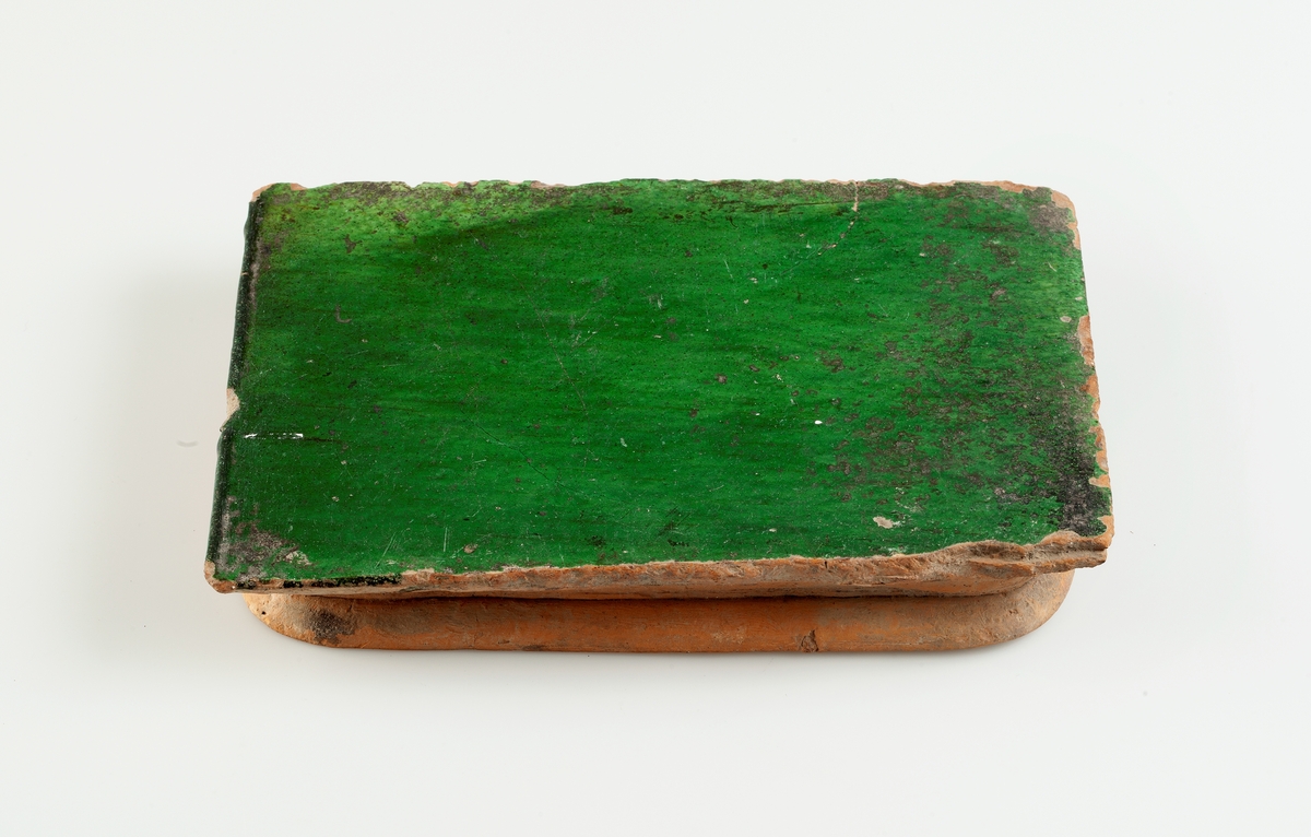 Kakel till kakelugn. Flat med mörkgrön glasyr.