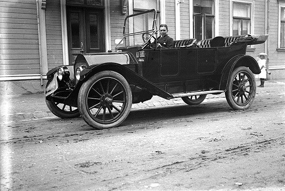 Olle Andersson i en bil av märket  Nyberg 40Hp (Model 4-40) 7-Passenger Touring 1913 
Bilden är tagen utanför Karl Nyströms ateljé på Södra Klaragatan 2.