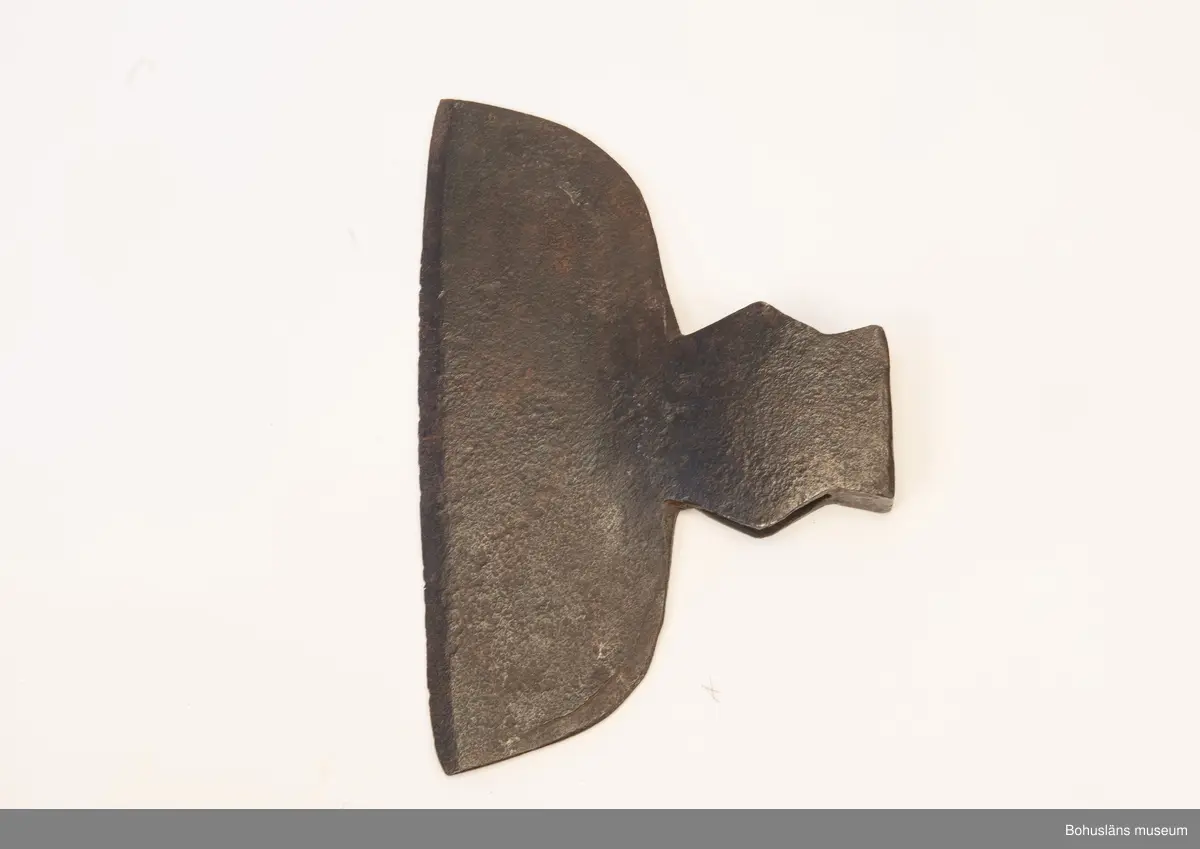 Handsmidd enkeleggad bred yxa med romboid holk med rektanguulärt uttag för skaft. Yxskaft saknas.
Viss gravrost.
Förvärvad 1952 från Johannes Olsson, Stillingön, Orust och då med uppgiften att yxan använts som bödelsyxa.

Svårbedömd tillverkningstid.

Ur handskrivna katalogen 1957-1958:
Bödelsyxa
L. 36,5. Br 24,5. Föremålet helt. Något rostat.