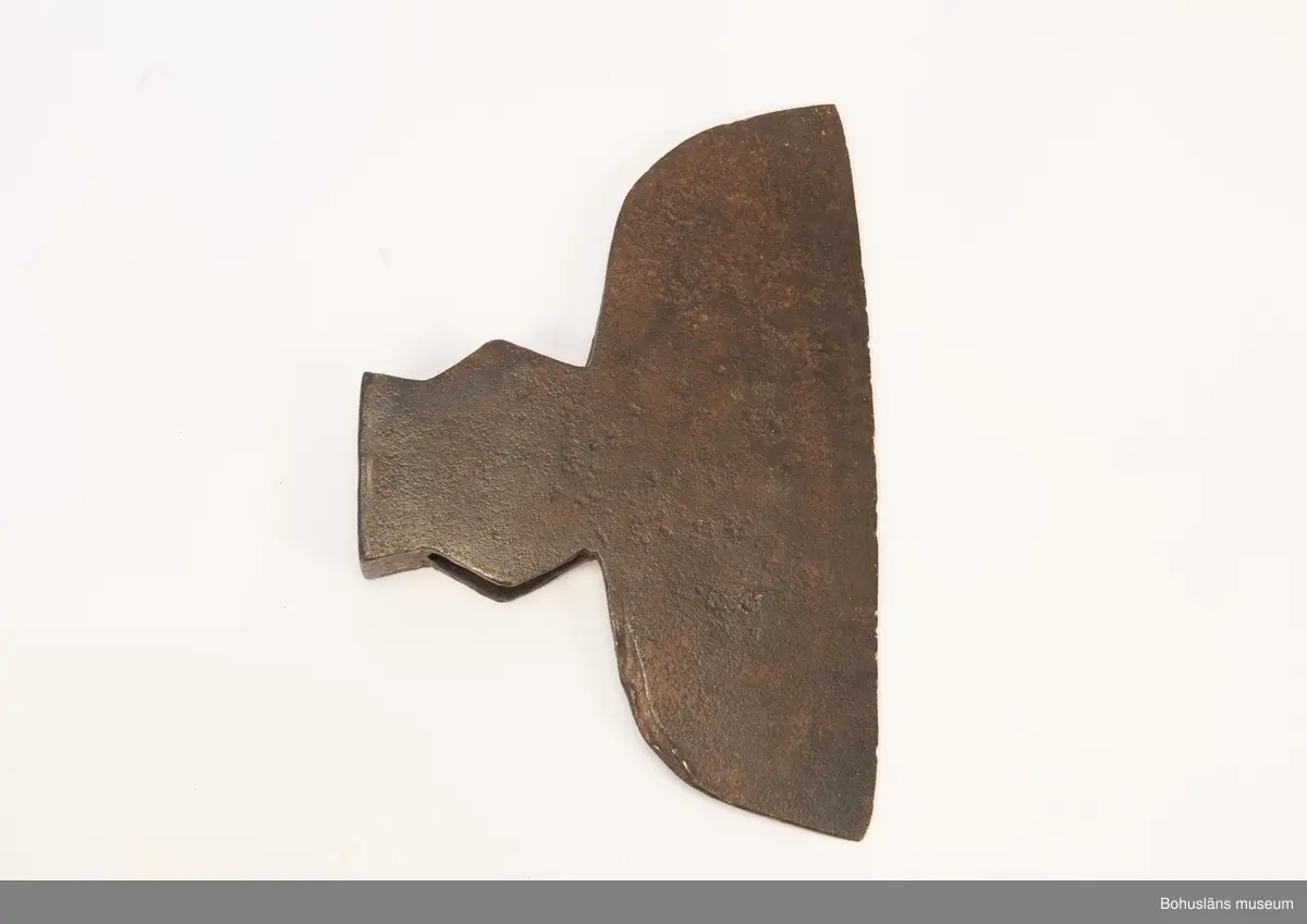Handsmidd enkeleggad bred yxa med romboid holk med rektanguulärt uttag för skaft. Yxskaft saknas.
Viss gravrost.
Förvärvad 1952 från Johannes Olsson, Stillingön, Orust och då med uppgiften att yxan använts som bödelsyxa.

Svårbedömd tillverkningstid.

Ur handskrivna katalogen 1957-1958:
Bödelsyxa
L. 36,5. Br 24,5. Föremålet helt. Något rostat.
