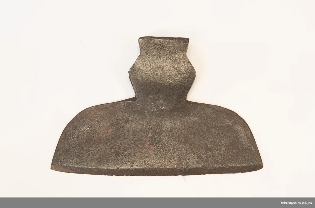 Handsmidd enkeleggad bred yxa med romboid holk med rektanguulärt uttag för skaft. Yxskaft saknas.
Viss gravrost.
Förvärvad 1952 från Johannes Olsson, Stillingön, Orust och då med uppgiften att yxan använts som bödelsyxa.

Svårbedömd tillverkningstid.

Ur handskrivna katalogen 1957-1958:
Bödelsyxa
L. 36,5. Br 24,5. Föremålet helt. Något rostat.