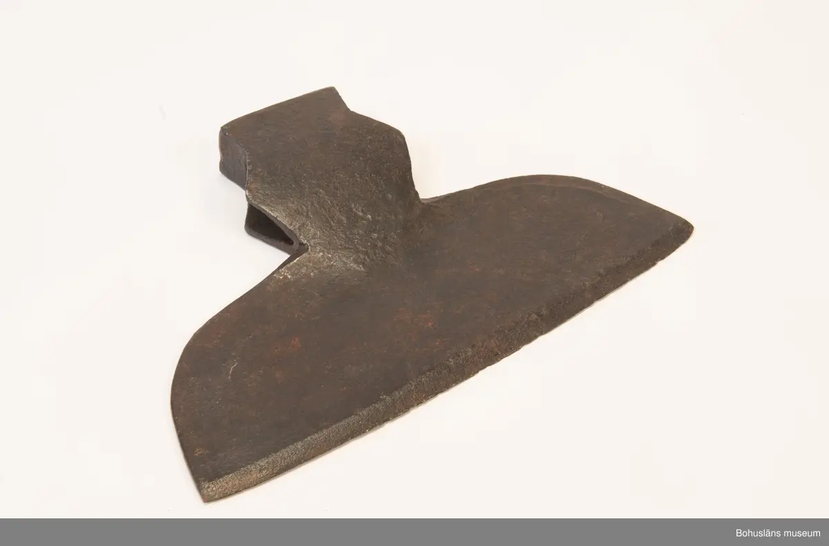 Handsmidd enkeleggad bred yxa med romboid holk med rektanguulärt uttag för skaft. Yxskaft saknas.
Viss gravrost.
Förvärvad 1952 från Johannes Olsson, Stillingön, Orust och då med uppgiften att yxan använts som bödelsyxa.

Svårbedömd tillverkningstid.

Ur handskrivna katalogen 1957-1958:
Bödelsyxa
L. 36,5. Br 24,5. Föremålet helt. Något rostat.