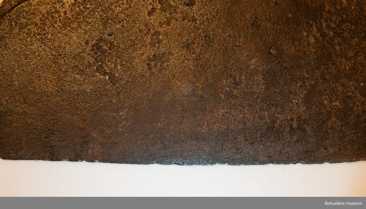 Handsmidd enkeleggad bred yxa med romboid holk med rektanguulärt uttag för skaft. Yxskaft saknas.
Viss gravrost.
Förvärvad 1952 från Johannes Olsson, Stillingön, Orust och då med uppgiften att yxan använts som bödelsyxa.

Svårbedömd tillverkningstid.

Ur handskrivna katalogen 1957-1958:
Bödelsyxa
L. 36,5. Br 24,5. Föremålet helt. Något rostat.