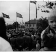 Folksamling med vuxna och barn i Braheparken i Gränna i samband med Eriksgata. Hissade flaggor.