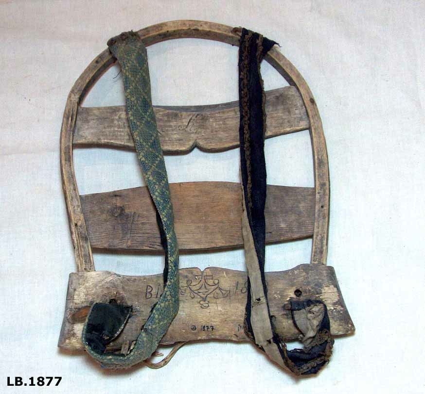 Bakmeis av ask med selar av tøy. Den eine selen er brodert med ullgarn. Den andre er i stoff med admiralband kring langsidene. Innskore bokstavar og årstal: B.I.S. 1813.