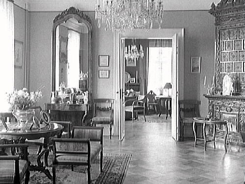 Interiör av salongen hos borgmästare Johan H L Janssen i det ena sk Tvillinghuset i kv Komedianten, Kungsgatan 5. Visar två rum i fil med en reslig kakelugn till höger om döbattangen (dubbeldörr) och en takhög spegel på andra sidan. Rummen har parkettgolv och kristallkronor.