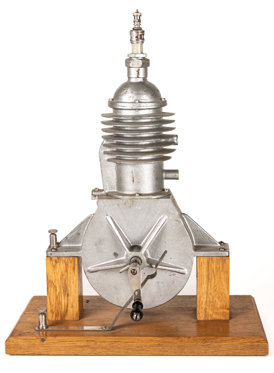 Modell av cylinder, vevstake och kolv i genomskärning. Järn, trä. Invändigt målad svart, röd och blå. Metalletikett med text "P.A. Norstedt & Söner Stockholm".