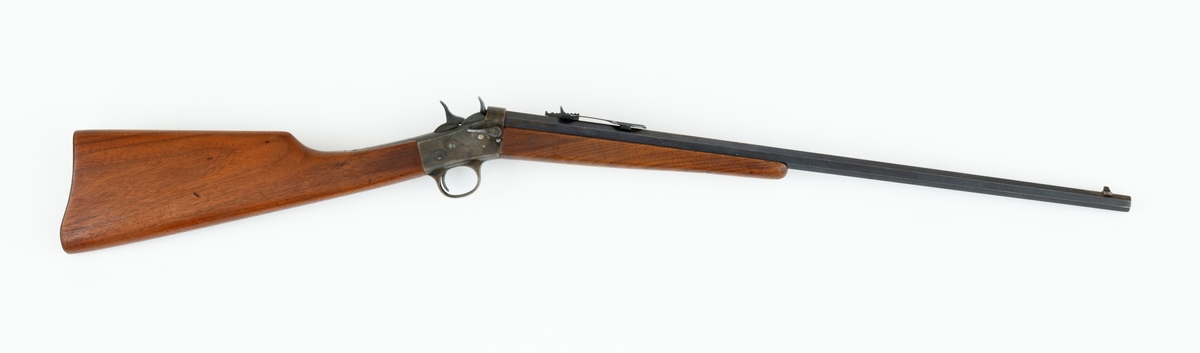 Tillegg innskrift: Remington TRADE MARK MODEL 4 25-10 R. F. Geværet har brunt, oljebehandlet treverk. Framstillingsnummeret er J 304870. Laget ca. 1870. Av størrelse kan geværet se ut som ei salongrifle, men kaliberet, 25-10, er litt større enn på Krag. R. F. står for Rand Fire (randtenning. ) 10-tallet står for 10 gram svartkrutt. Dvs. ca. 4 gram. Dette er en meget kraftig ladning, nesten like mye som på den store Remington. Det må være en av de raskeste svartkruttpatroner som er laget.