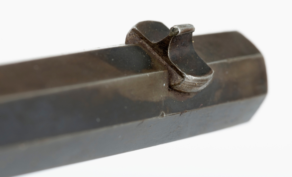 Tillegg innskrift: Remington TRADE MARK MODEL 4 25-10 R. F. Geværet har brunt, oljebehandlet treverk. Framstillingsnummeret er J 304870. Laget ca. 1870. Av størrelse kan geværet se ut som ei salongrifle, men kaliberet, 25-10, er litt større enn på Krag. R. F. står for Rand Fire (randtenning. ) 10-tallet står for 10 gram svartkrutt. Dvs. ca. 4 gram. Dette er en meget kraftig ladning, nesten like mye som på den store Remington. Det må være en av de raskeste svartkruttpatroner som er laget.