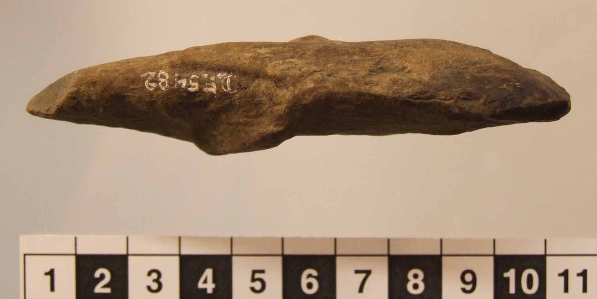 Tunnackig yxa, med spetsovalt tvärsnitt. Kraftigt vittrad. Spetsovalt tvärsnitt. Sned något utsvängd egg.
