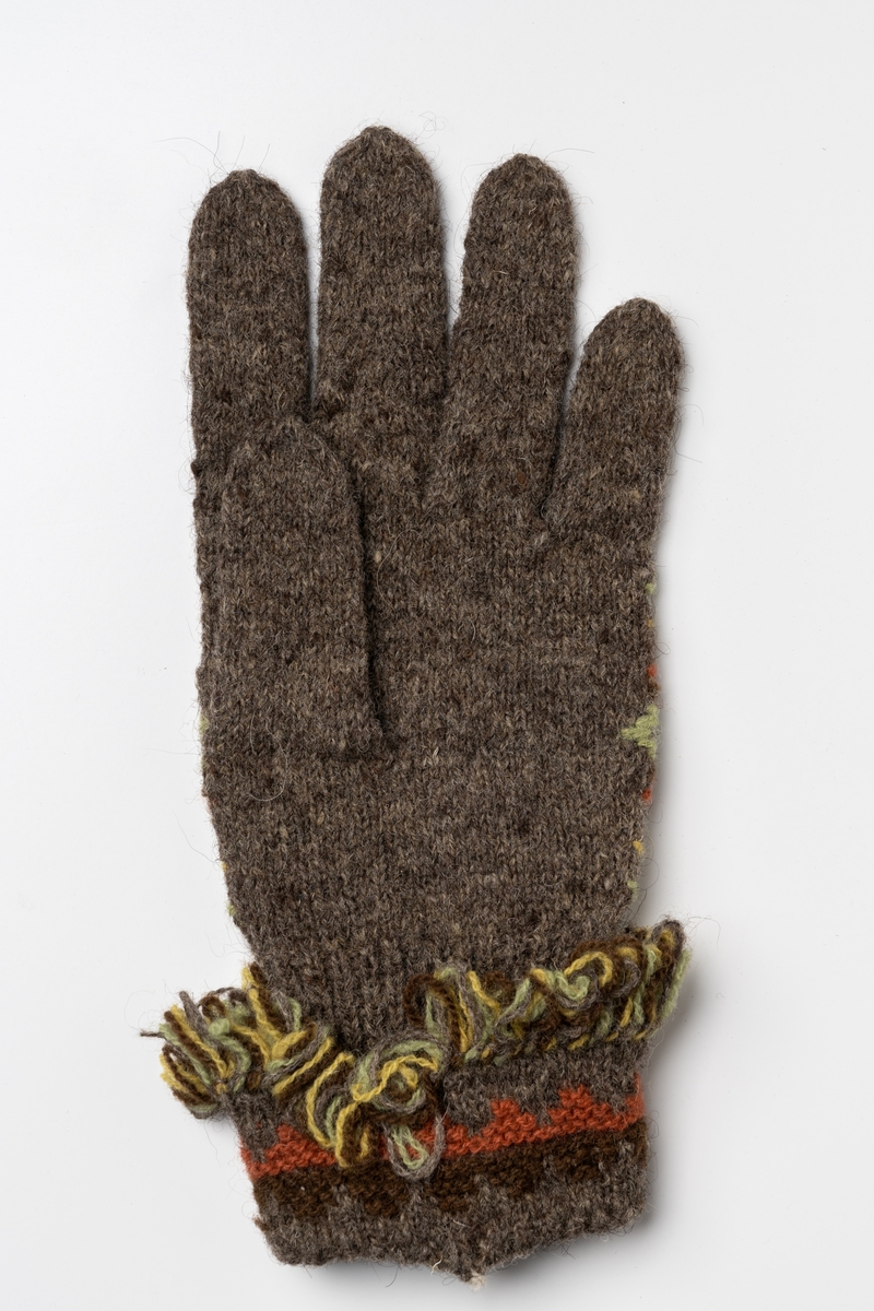 Fingervante, slätstickad vante av mörkgrått ullgarn. Ovansidan har broderat stjärnmönster i fyra färger; brunt, röd-brunt, grönt och gult. Mudden har en nervikt krage, mönsterstickad i trianglar och försedd med kavelfrans i kanten. Jämför: JM.37041:1.