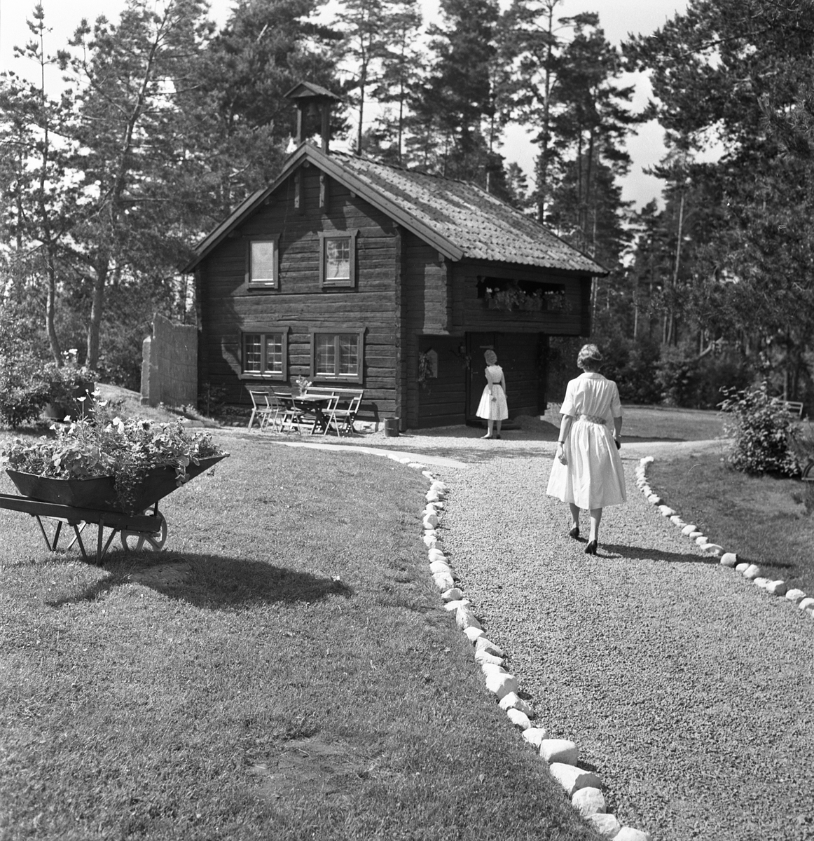 Motiv från populära sommarserveringen i Tallboda. Året är 1958 och tionde säsongen för ägarna tillika makarna Sven-Gerhard och Sonja Larsson. Serveringen hade de startat 1949 på Sonjas initiativ. Sven-Gerhard arbetade som frisör i Linköping men hjälpte till med all tid därutöver. Den timrade loftboden i blickfånget hade flyttats till platsen just detta år för att främst tjäna som servering vid sämre väder. Den var hämtad från Dalhem och i sammanhanget kan nämnas att den år 2005 kom att flyttas till Landeryds hembygdspark.