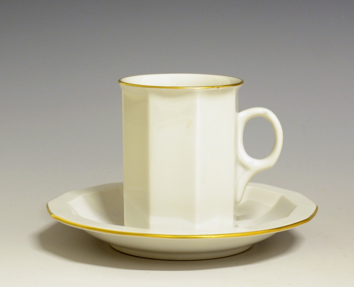 Mangekantet kopp i porselen med kantstrek i gull og logo i form av en rød gryte med lokk og påskriften "Til Bords". Hvit glasur.
Modell: Octavia, tegnet av Grete Rønning i 1977.