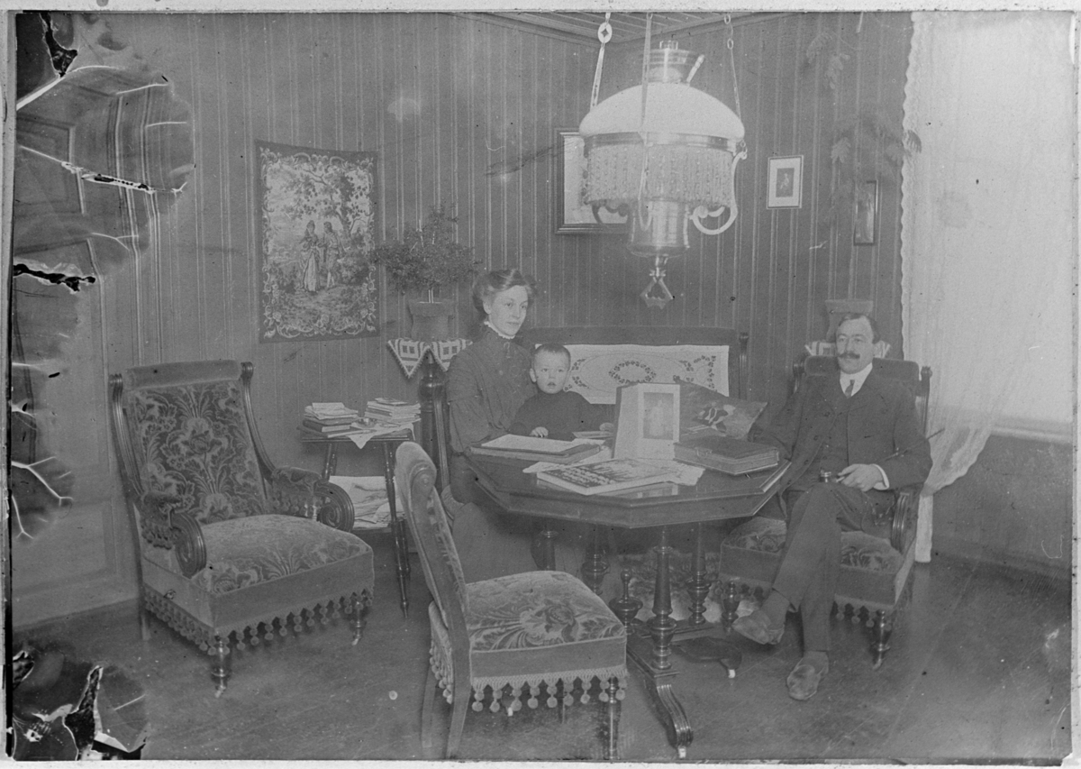 Stueinteriør med ukjent familie. Trolig fotografert i Kristiania omkring 1910.