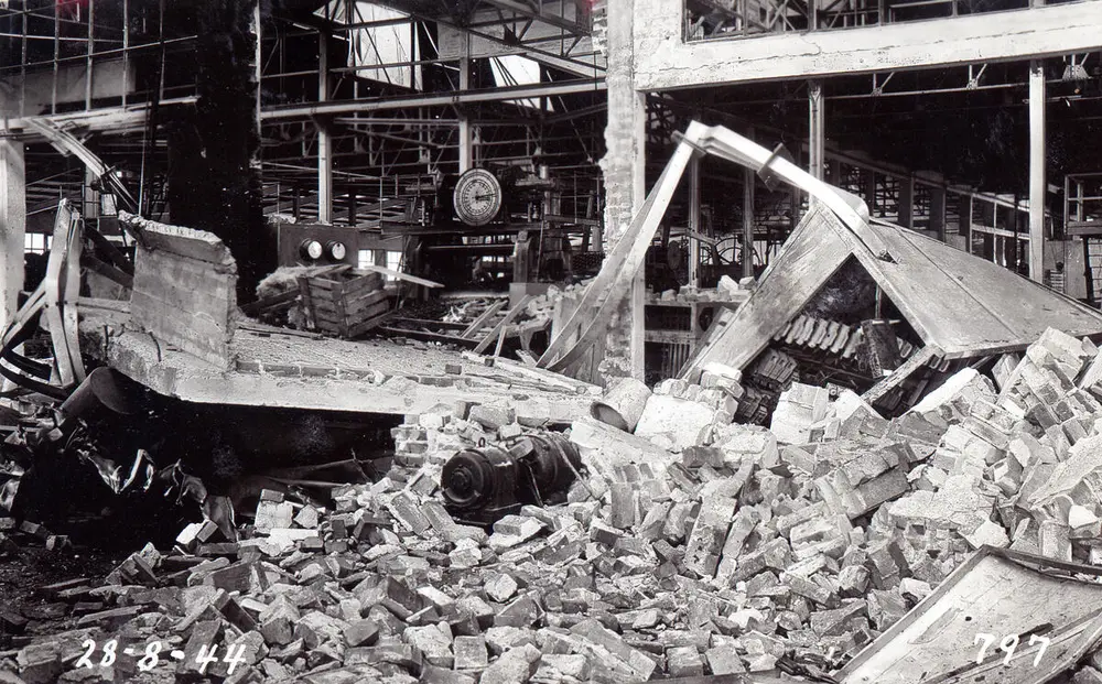 Sort-hvitt bilde av en nedrast bygning. Vi ser mengder med betong og armeringsjern.