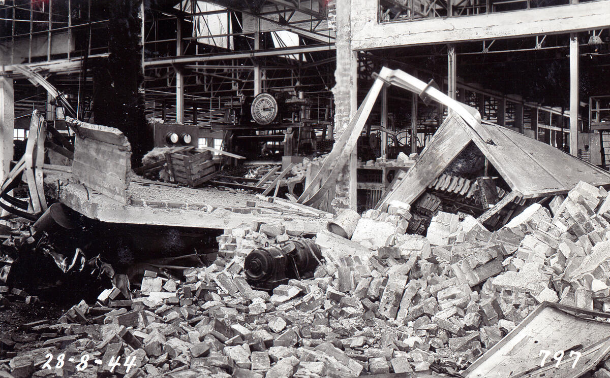 Sort-hvitt bilde av en nedrast bygning. Vi ser mengder med betong og armeringsjern.