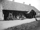 Motiv från fotografens besök av Sjöbacka i Ljung 1895. Vid bänken sitter familjen Tydén som arrenderat gården sedan 1889.