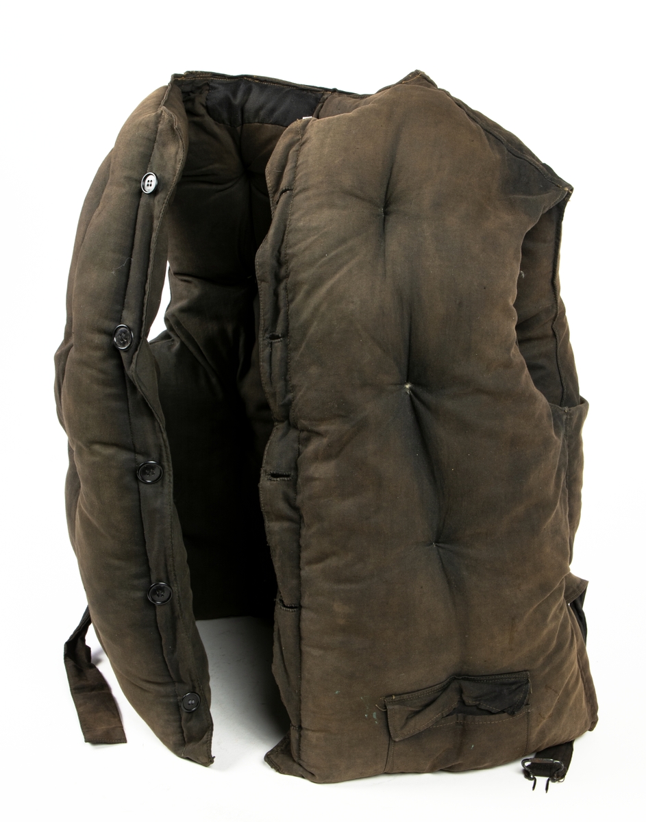 Flytväst Tjockt vadderad mörkbrun flytväst. Enkelknäppt med fem knappar, en ficka på vänster framstycke. Förmodligen vadderad med Kapok.