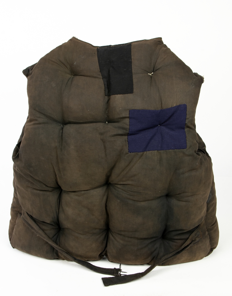Flytväst Tjockt vadderad mörkbrun flytväst. Enkelknäppt med fem knappar, en ficka på vänster framstycke. Förmodligen vadderad med Kapok.