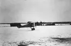 Flygplan FVM Tummeliten nr 197 startar från Malmen, vintertid omkring 1922-1926. I bakgrunden syns transformator och stallbyggnad.