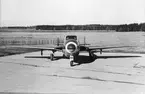 Flygplan J 28C märkt nr 93 står uppställd på platta, omkring 1959-1968. Vy framifrån.